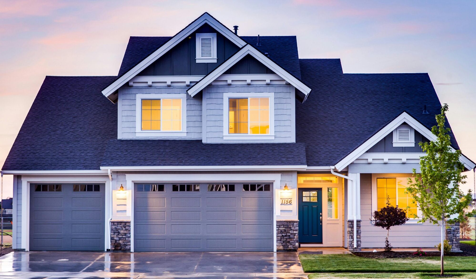 Beautiful two-story house with illuminated windows and garage at dusk.