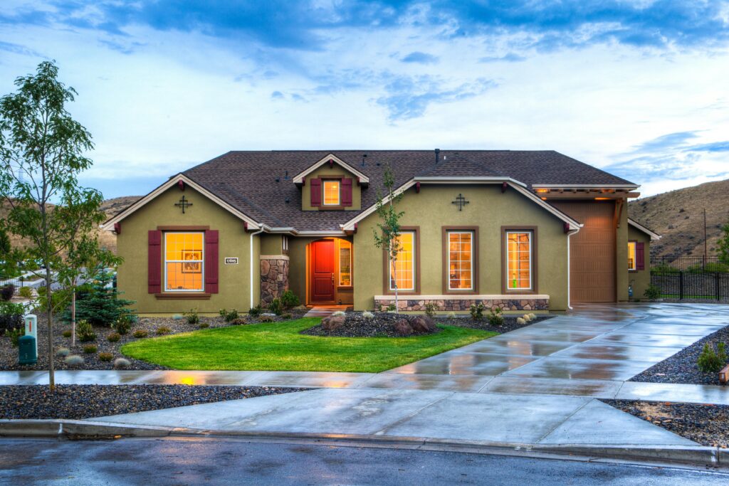 Beautifully illuminated modern home exterior with a lush lawn and wet driveway in Boise, Idaho.